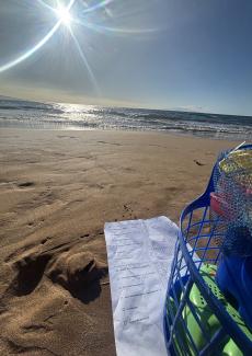 There is sand, the ocean, a page of math homework, and a bucket of sand toys