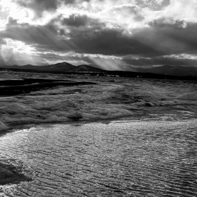 Black and white photo of people walking along winter shore