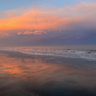 A bright sunset reflects against the ocean.