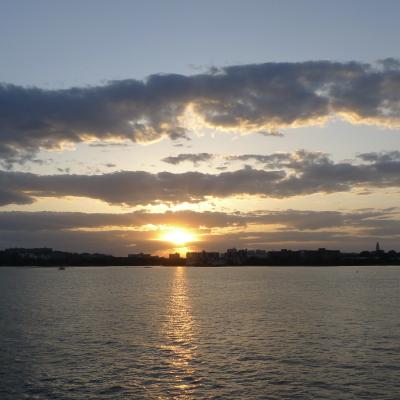 A photograph of a sunset over a river, with gold and orange clouds lit by the sun.